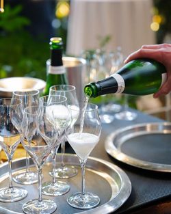 Champagne being poured into flute glasses on a silver tray with bottles and another tray in the background.