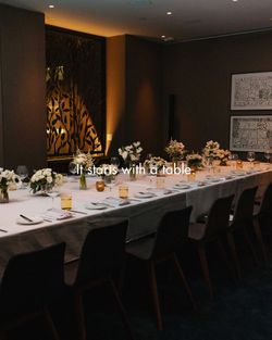 Long dining table set with white tablecloth and floral centerpieces at Le Pavillon in NYC midtown.