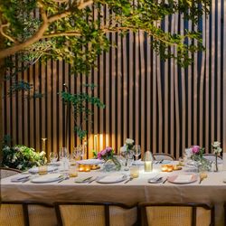 Elegant dining table set with white linen, glassware, candles, and fresh flowers in a modern setting at Le Pavillon.