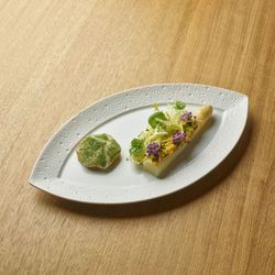 Fine dining dish at Le Pavillon with an artistic presentation featuring edible flowers and delicate greens on a white plate.
