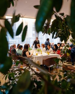 Elegant dining room at Le Pavillon with guests seated at tables, attended by waitstaff in a well-lit setting.