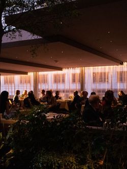 Dimly lit fine dining area in a Midtown bar with guests seated at tables during evening hours.