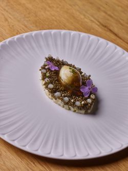 Fine dining dish featuring caviar and edible flowers served on a textured white plate at Le Pavillon.