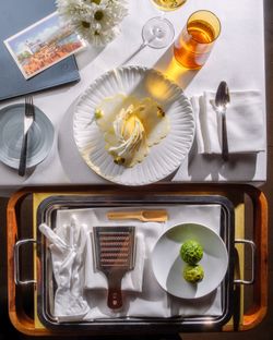 A top-down view of a dining table with a beautifully plated dish, utensils, and a drink, showcasing fine dining.