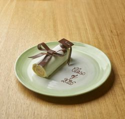 Delicate rolled dessert with a chocolate bow on a plate inscribed with "Class of 2026" at Le Pavillon.