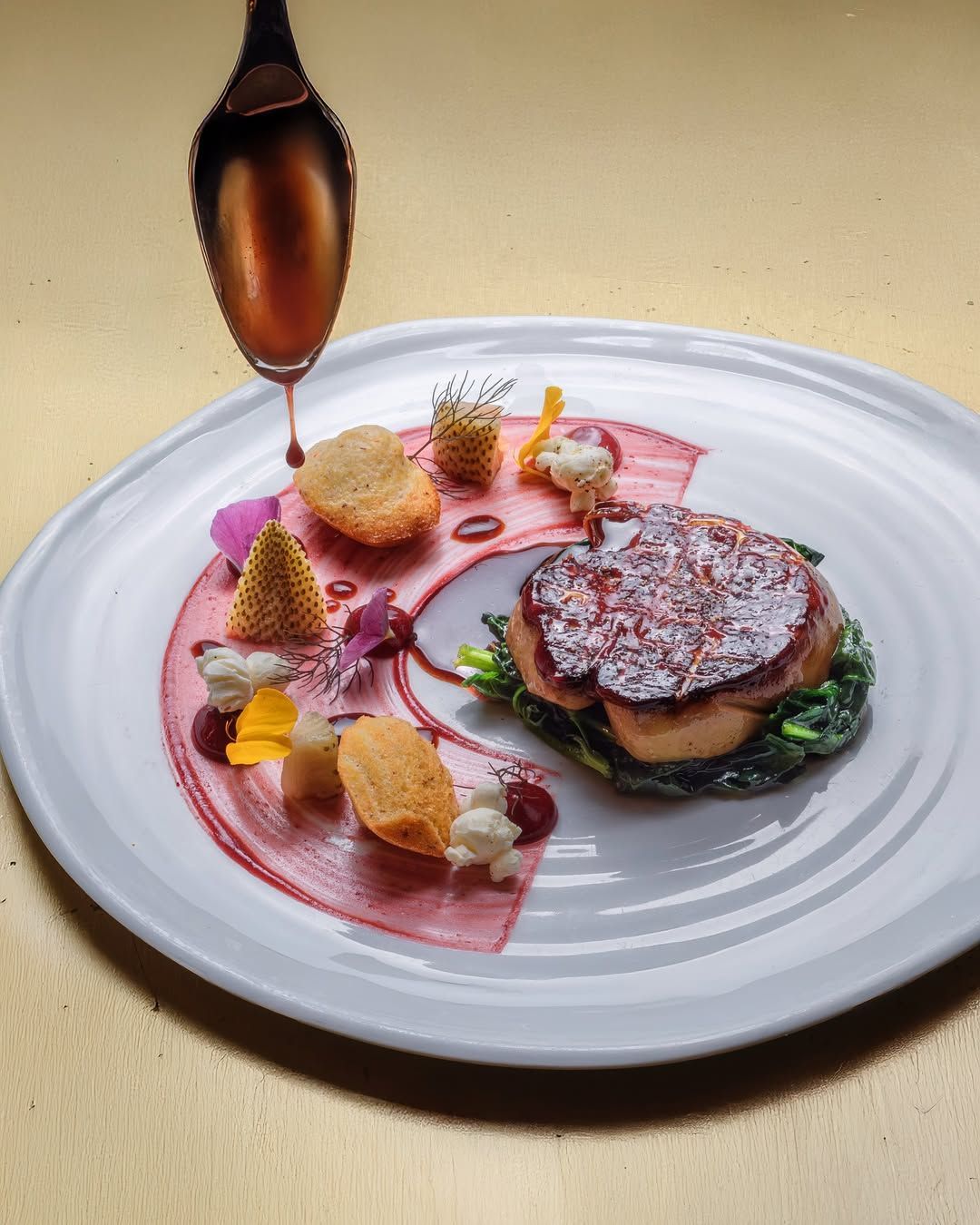 Plated gourmet dish featuring a beautifully arranged protein with colorful garnishes and sauces.