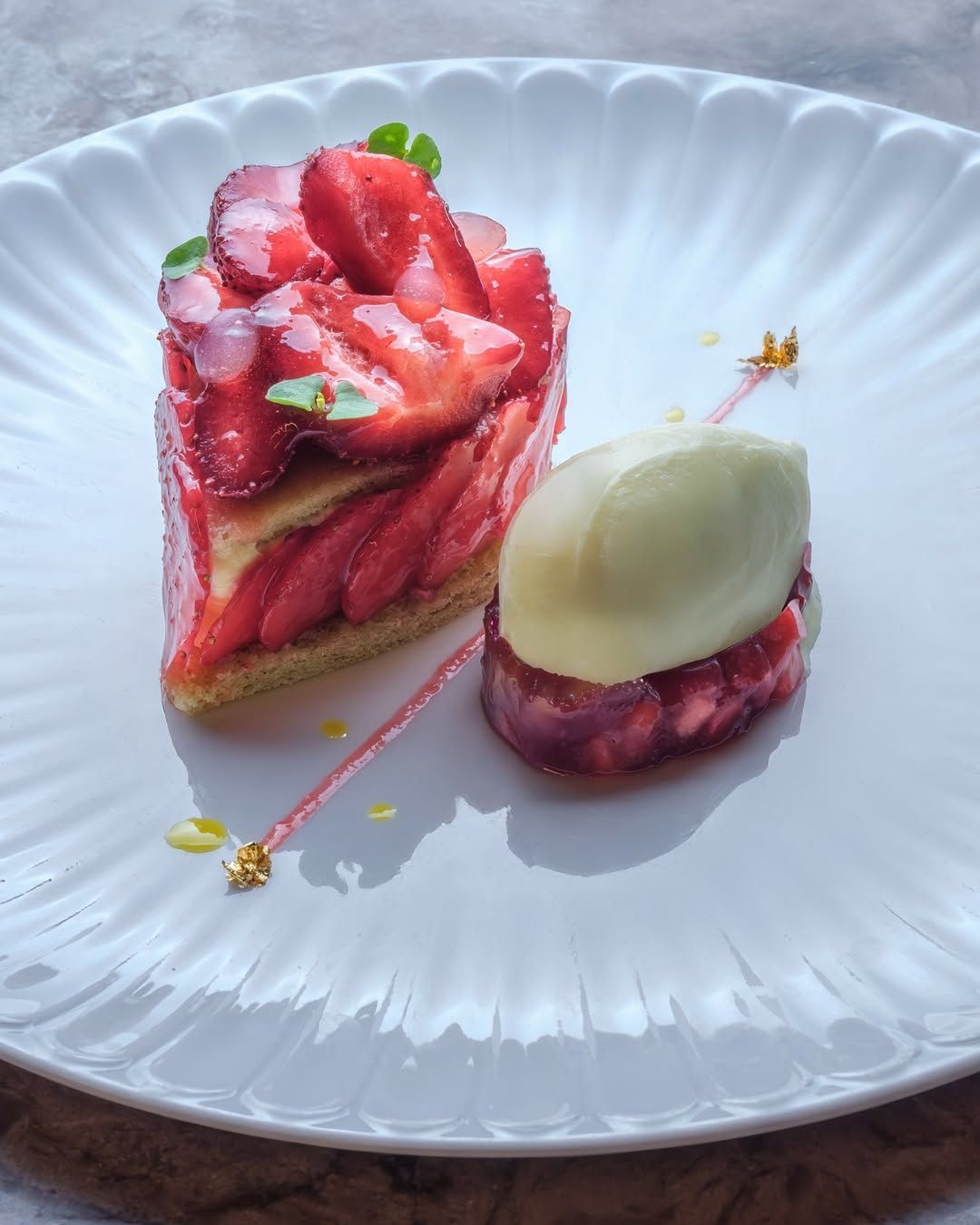 A beautifully plated dessert featuring layers of fresh strawberries and cream, accompanied by a scoop of sorbet.